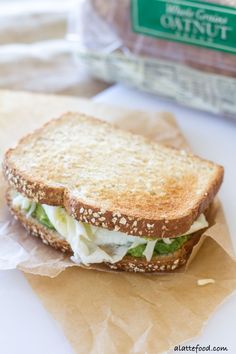 a sandwich with lettuce and mayonnaise sitting on top of brown paper