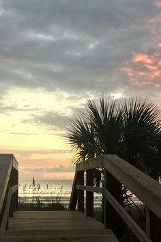 a wooden walkway leading to the beach at sunset