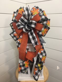 a large bow with leaves on it sitting on top of a wooden stand in front of a white wall