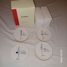 four white plates sitting on top of a bed next to a box