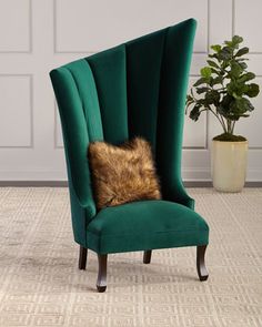 a green chair with a fur pillow on it's back in front of a potted plant