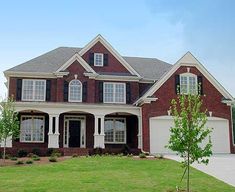 a large brick house with white trim on the front and side windows, grass in front