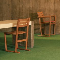 two wooden chairs sitting next to each other on top of a green carpeted floor