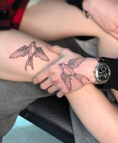 two people holding hands with tattoos on their arms, one has a humming tattoo on it's arm