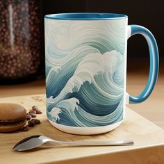 a blue and white coffee mug sitting on top of a wooden table next to a spoon