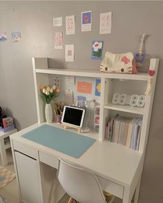 a white desk with a computer on top of it next to a book shelf filled with books