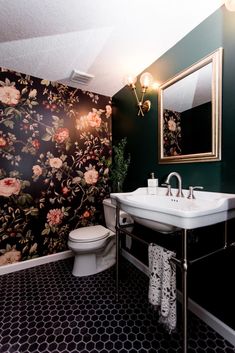 a bathroom with floral wallpaper and black flooring