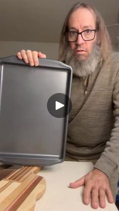 a man with a beard is holding up a laptop computer that looks like it has been built