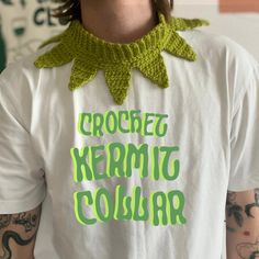 a man wearing a crochet kermito collar t - shirt with green lettering