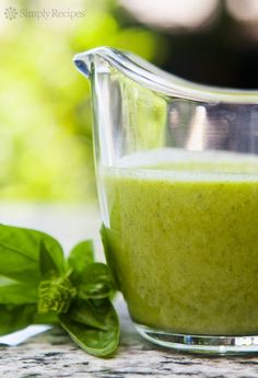 a green smoothie in a blender next to some leaves