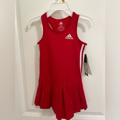 a red tennis dress hanging on a door hanger with the name adidas printed on it