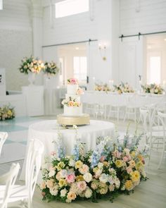 a wedding cake sitting on top of a white table covered in lots of colorful flowers