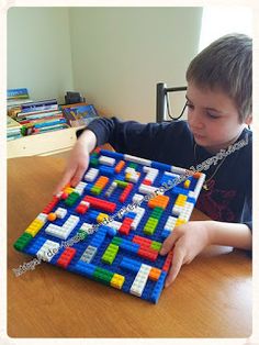 a young boy is playing with a lego board