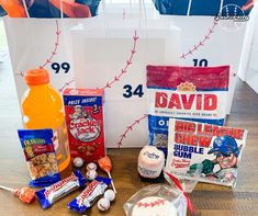 some snacks are sitting on a table next to bags and bottles with baseballs in them