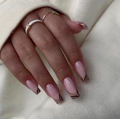 a woman's hand with pink and black manies on it, wearing a white sweater