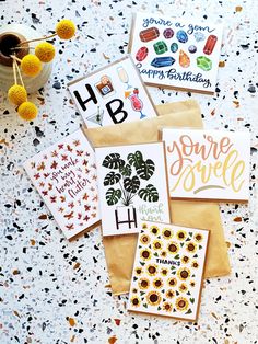 some cards are laying on the ground next to a potted plant and a cup