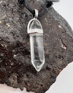 a clear quartz pendant on a black cord