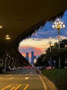 an empty street at dusk with cars parked on the side