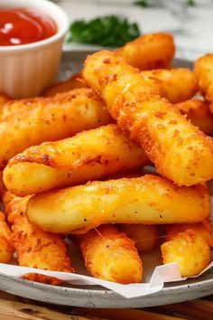 some fried food on a plate with ketchup and dipping sauce in the background