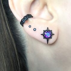 an ear with two piercings attached to it's sides and one has a purple stone in the middle