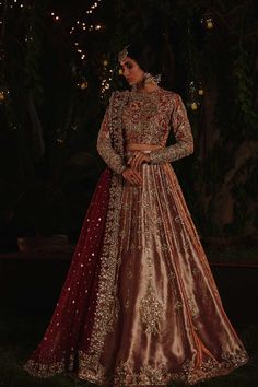 a woman in a red and gold lehenga standing on the grass at night