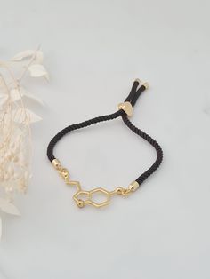 Cute gold plated serotonin cord bracelet.  This bracelet is adjustable with a slider clasp.  Choose your cord colour.  This bracelet will fit up to a medium sized hand. Serotonin charm measures 4cm x 1.5cm. This item ships from the UK within 1 working day.