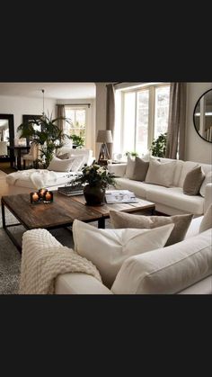 a living room filled with white furniture and lots of mirrors on the wall above it