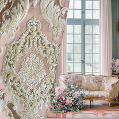 a living room filled with furniture next to a window covered in pink and gold wallpaper