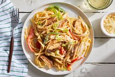 a white plate topped with pasta and meat next to a bowl of sauce on top of a table