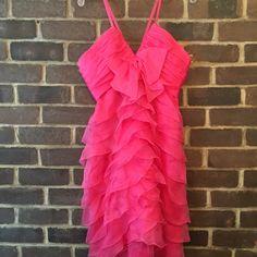 a pink dress hanging on a brick wall