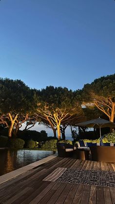 an outdoor deck with chairs and umbrellas next to the water