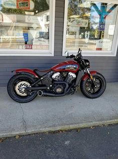 a red motorcycle parked in front of a store