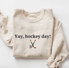 a sweater with the words yay, hockey day on it and two crossed sticks