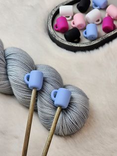 two skeins of yarn and some knitting needles on a white furnishing