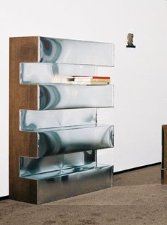 a book shelf sitting on top of a carpeted floor next to a white wall