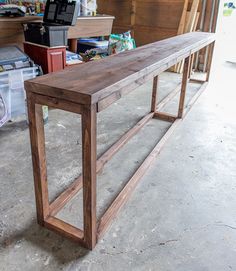 a long wooden table sitting inside of a room next to other items on the floor