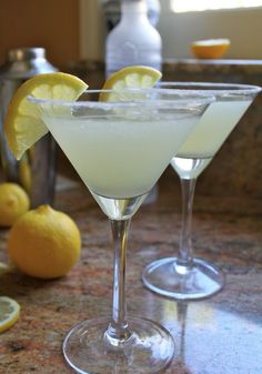 two martini glasses filled with white liquid and lemon wedges on a granite countertop