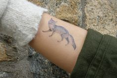 a cat tattoo on the wrist of a person's arm, which is covered in wool