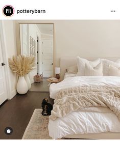 a cat laying on the floor in front of a bed with white sheets and pillows