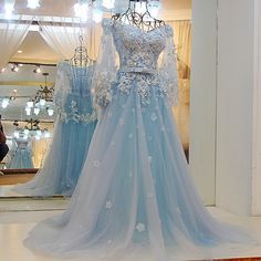 a blue wedding dress is on display in front of a mirror with lights behind it