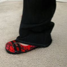 a person wearing red and black shoes standing on top of a white carpeted floor