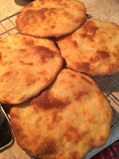 four cheese pizzas cooling on a rack