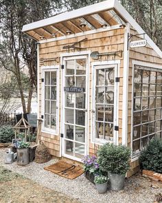 a small wooden building with glass doors and windows on the outside, surrounded by potted plants