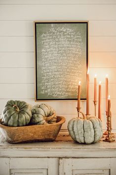 a table with candles, pumpkins and a chalkboard on the wall behind it