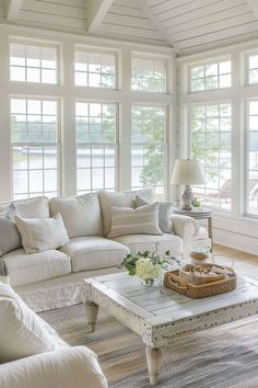 a living room filled with white furniture and lots of windows covered in shades of light