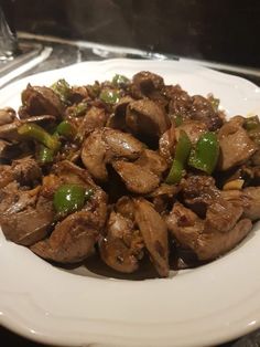 a white plate topped with meat and green peppers