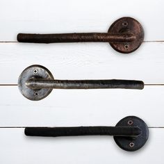 three old door handles and knobs on a white wooden wall