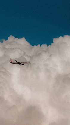 an airplane is flying through the clouds on a sunny day