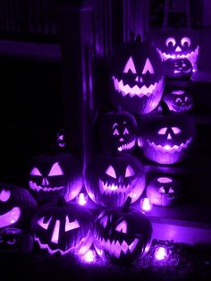 many carved pumpkins lit up in purple light