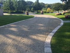 a gravel driveway with grass and trees in the background